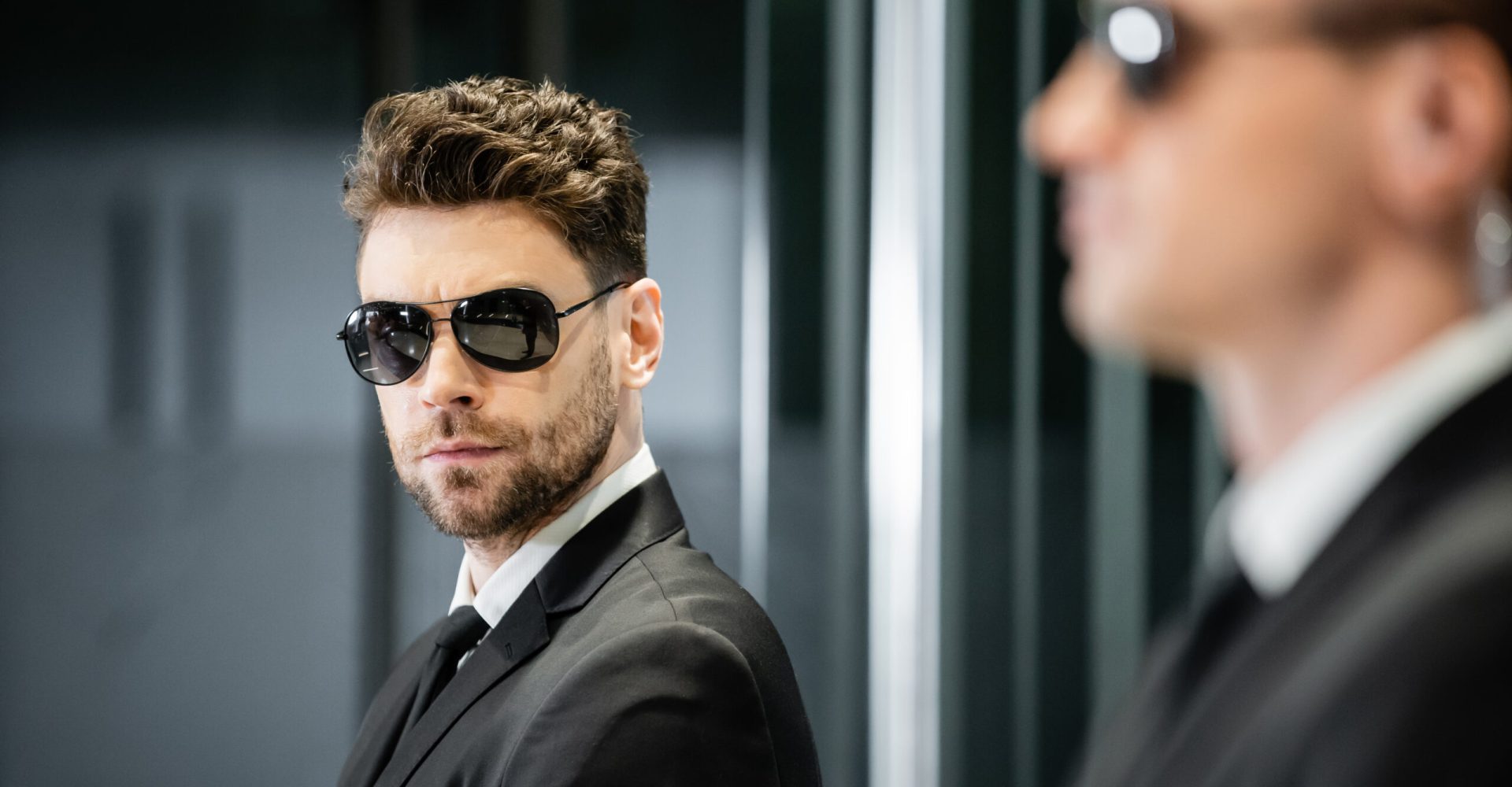 bodyguard service, private security, handsome man in suit and sunglasses standing in hotel lobby near work partner, vigilance, protection and career, professional headshots, looking at camera bodyguard service, private security, handsome man in suit and sunglasses standing in hotel lobby near work partner, vigilance, protection and career, professional headshots, looking at camera