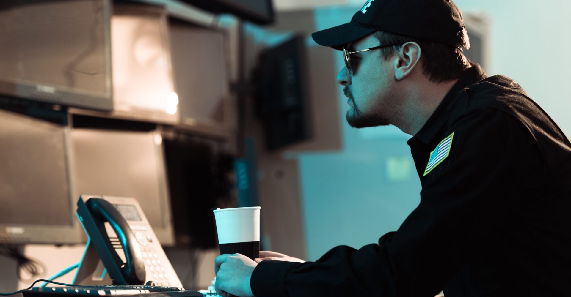 side view of prison guard sitting with cup of coffee and monitoring people in jail side view of prison guard sitting with cup of coffee and monitoring people in jail